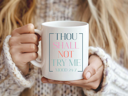 Person holding a mug with text 'THOU SHALL NOT TRY ME MOOD 24/7' held by a person.